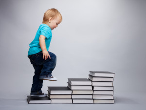 A toddler climbing on a steps made of books